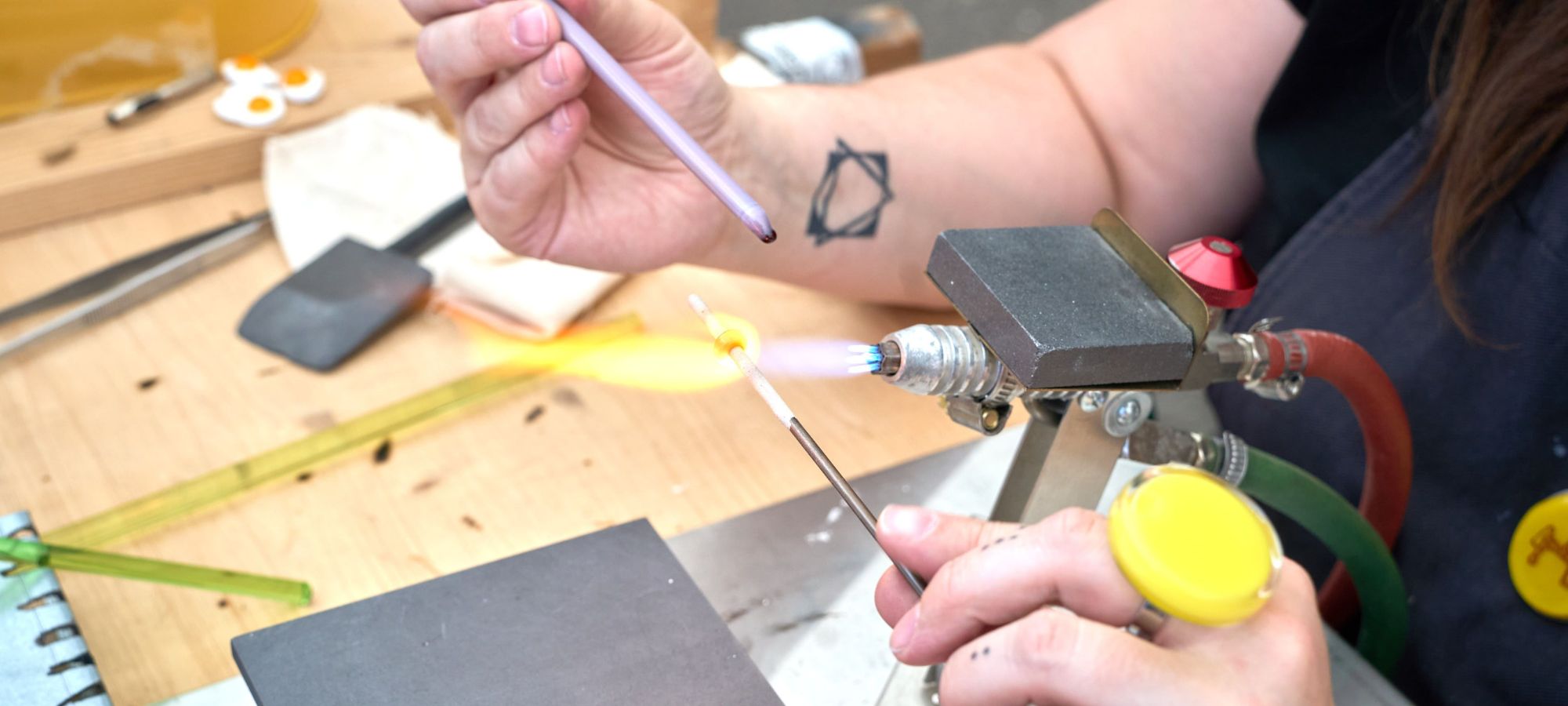 Bijoux personnalisés en verre filé Processus de création d'une perle de verre filé avec décors de lignes torsadées sous la flamme.